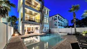 Un edificio de varios pisos con piscina, mobiliario exterior y palmeras.