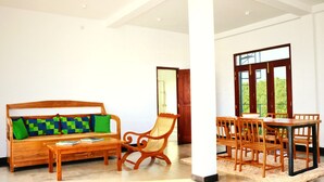Uma sala de estar moderna com um sofá de madeira, uma mesa de centro e uma área de jantar com cadeiras e mesa de madeira.