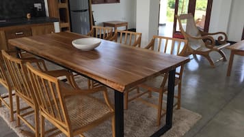 Un comedor con una mesa y sillas de madera, un bol en la mesa y una cocina al fondo.