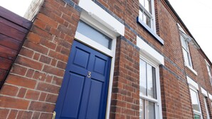 A brick building with a blue door marked with the number 3, white window frames, and a visible window above the door. - Highfield Grove -  a serviced house that sleeps 4 guests  in 2 bedrooms (Nottingham)