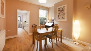 A dining area with a wooden table and chairs, a pendant light, and a wall clock. - Highfield Grove -  a serviced house that sleeps 4 guests  in 2 bedrooms (Nottingham)
