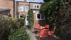 A brick house with a small patio area featuring a table and chairs. - Highfield Grove -  a serviced house that sleeps 4 guests  in 2 bedrooms (Nottingham)