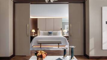 Ein Hotelzimmer mit einem großen Bett, Nachttischen, einer Kristallleuchtre und einer Blumenvase.