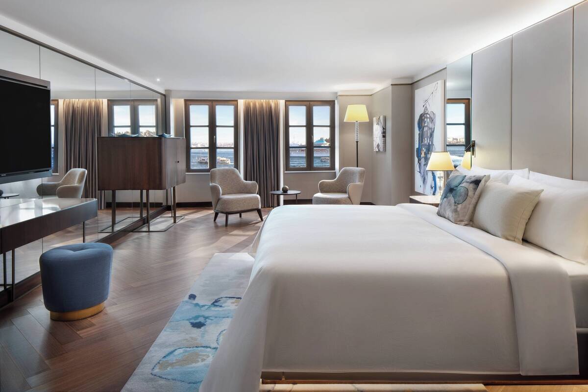 Una habitación de hotel moderna con una cama grande, dos sillones, un escritorio y un televisor.