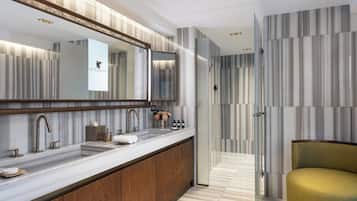 A modern bathroom with a large mirror, two sinks, and a wooden vanity.