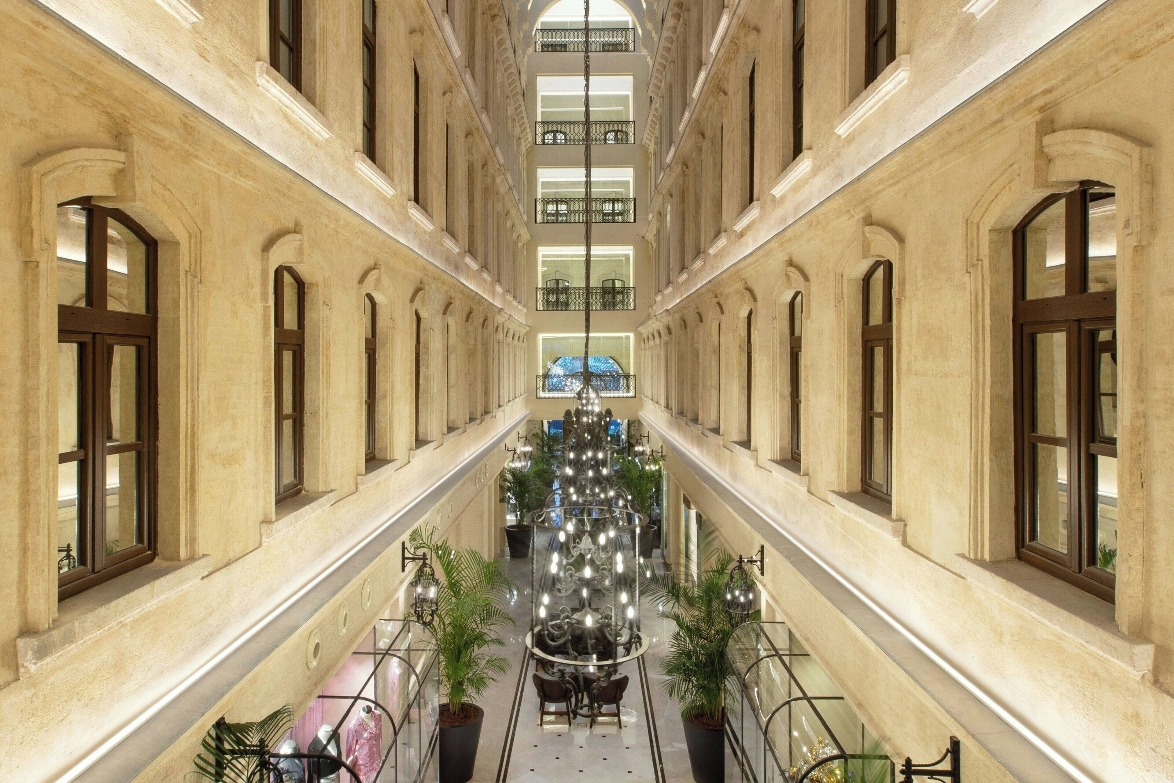 A grand, symmetrical interior with a central atrium, large windows, and a chandelier.