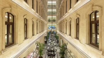 A grand, symmetrical interior with a central atrium, large windows, and a chandelier.