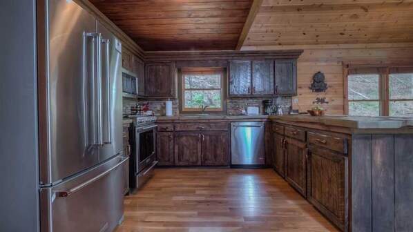 A kitchen with wooden cabinets, a stainless steel refrigerator, an oven, and a dishwasher.