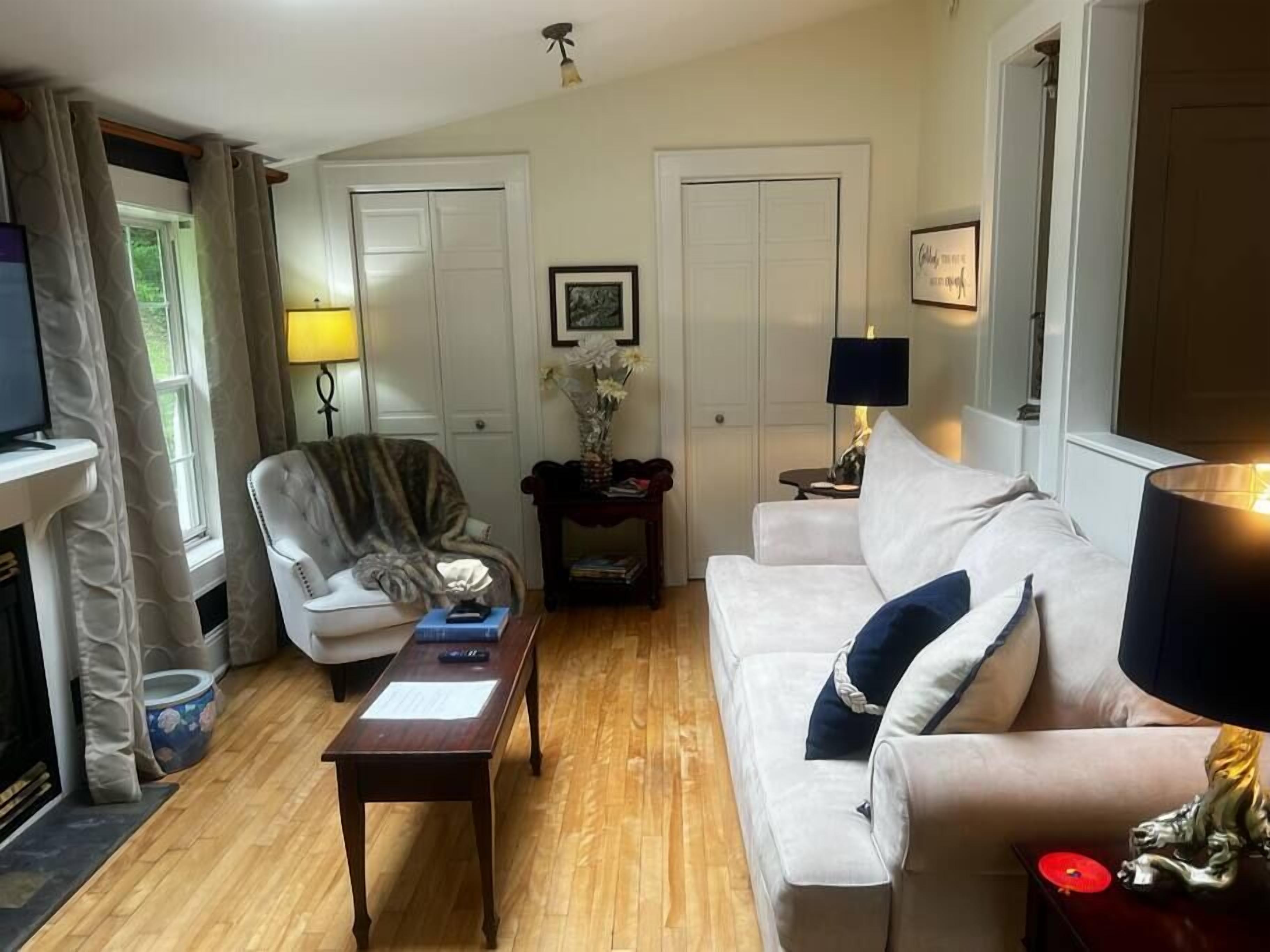 A living room with a white sofa, a chair, a wooden coffee table, a fireplace, and a television.