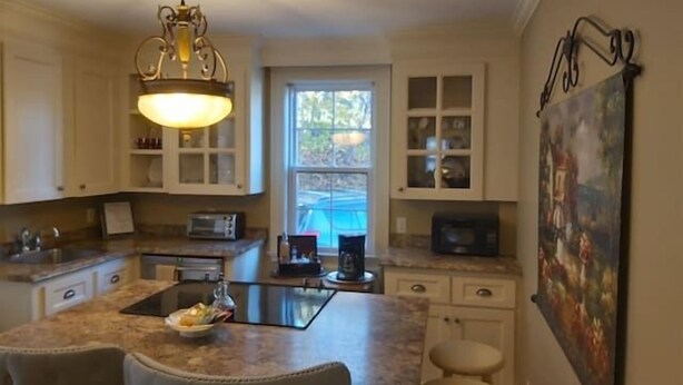 A kitchen with a central island, white cabinets, and a pendant light. - 1930'S Charming & Enchanted Unit By Waterfalls (Armdale)
