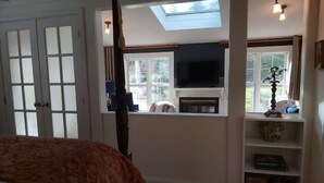 A bedroom with a large bed, a skylight, a fireplace, and a view of the outdoors. - 1930'S Charming & Enchanted Unit By Waterfalls (Armdale)