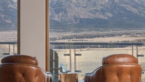 Une pièce avec deux fauteuils en cuir, placés face à une grande fenêtre donnant sur une vue sur les montagnes.