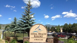 Señal de Ideal Beach Resort en el Lago Bear, con cielo despejado y montañas al fondo.