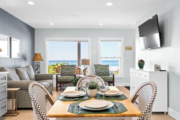 A dining area with a wooden table set for four, surrounded by wicker chairs with a zigzag pattern.
