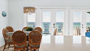 Ein Essbereich mit Korbstühlen und einem Tisch, mit Blick aufs Meer.