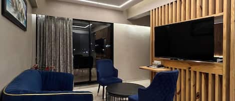 A modern living room with a sofa, chairs, a coffee table, and a TV.