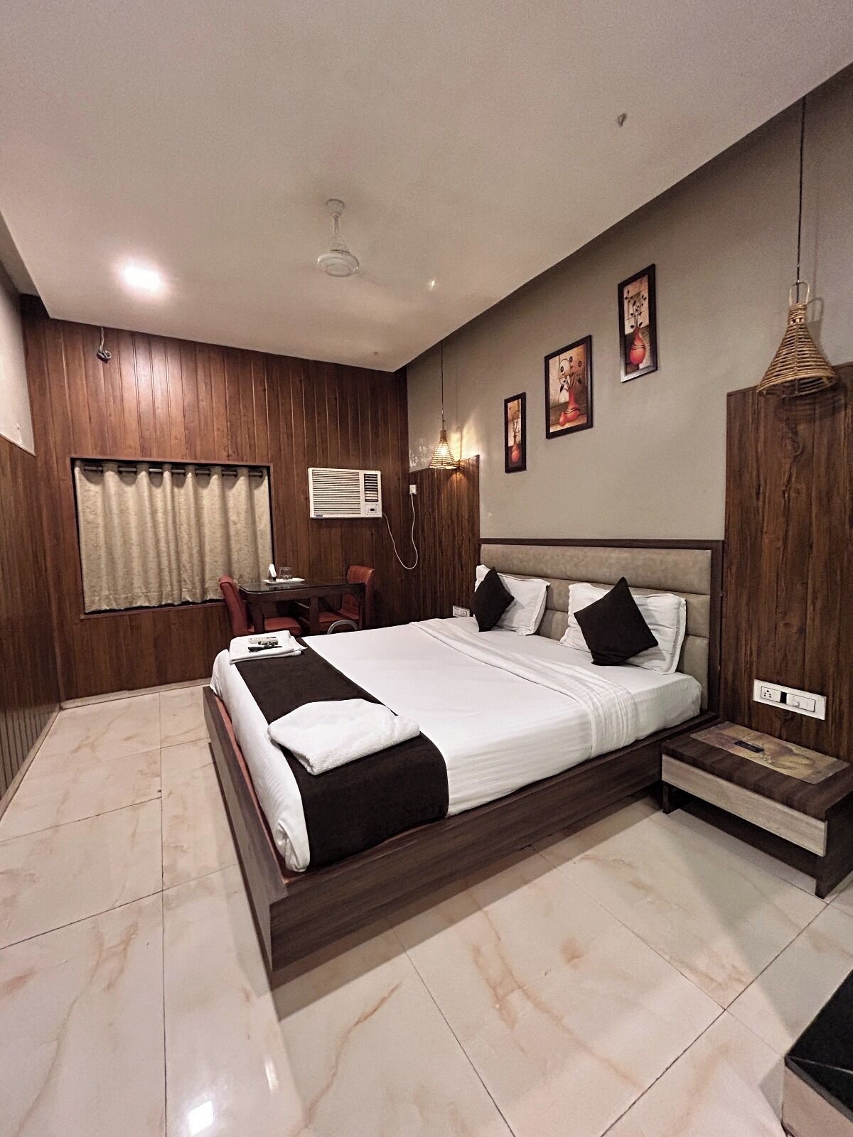 A modern bedroom with a large bed, wooden panel walls, a desk, and a chair.