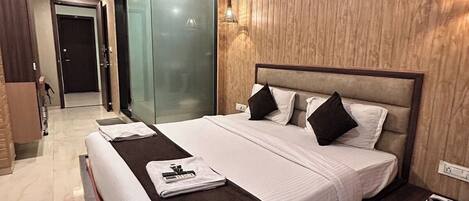 A modern hotel room with a large bed, a bedside table, a mirror, and a wardrobe.