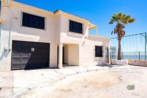 Un bâtiment à deux étages avec un garage, une véranda et un palmier.