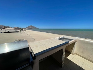 Un espace extérieur aménagé près de la plage, équipé d’un évier et d’un barbecue.