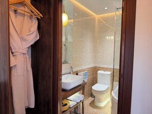 Une salle de bain moderne avec un meuble-lavabo en bois, un lavabo blanc, des toilettes et une douche séparée par une paroi en verre.