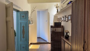 A hallway with a blue door, a wooden cabinet, and a shelf with framed pictures. - Usman Heritage Hotel (Bukhara)