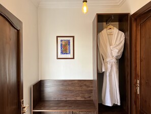 Een houten bank, een badjas hangt aan de deur en een lijst met een afbeelding aan de muur.