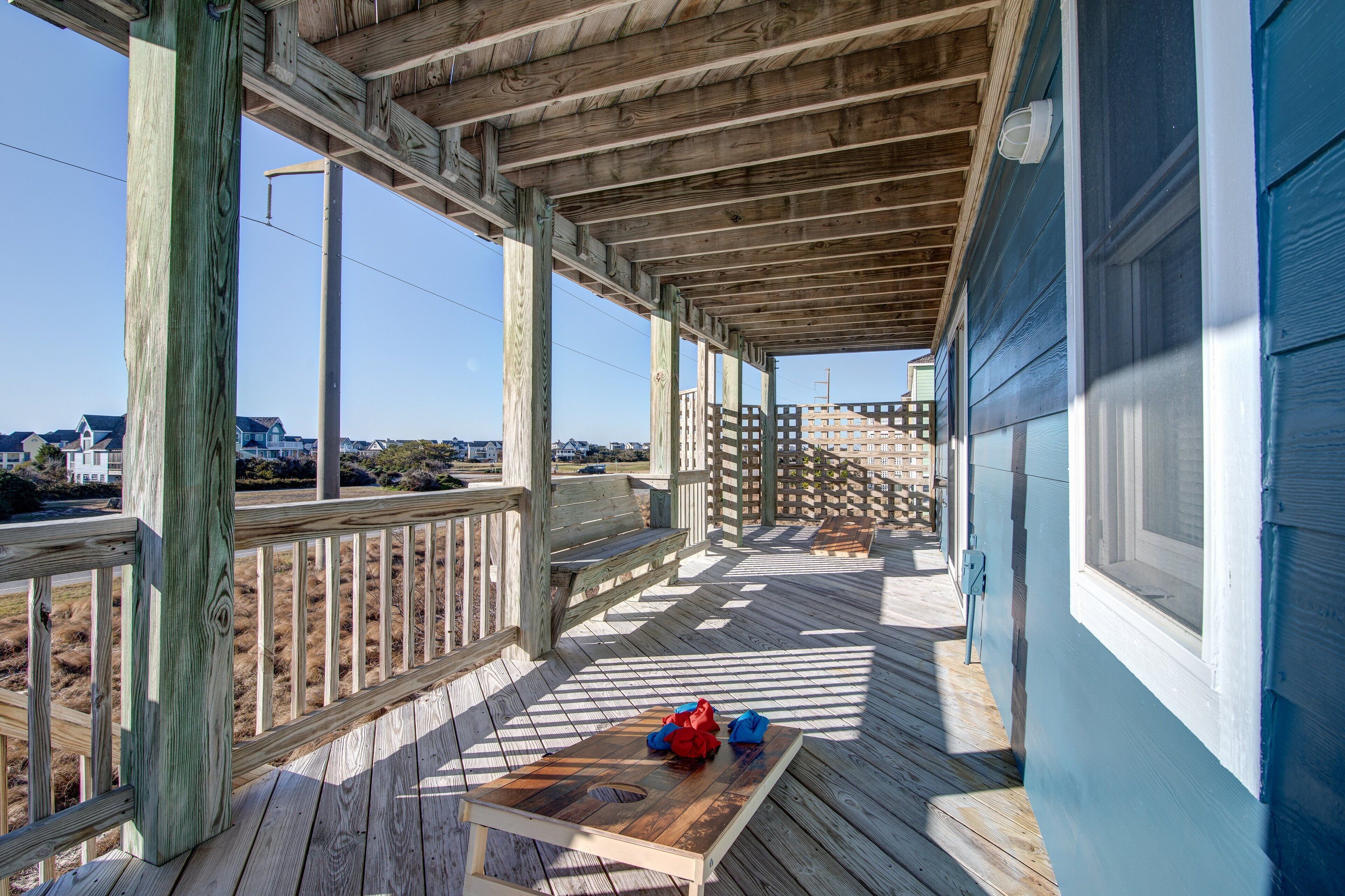 A wooden deck with a view of the beach and houses in the background.