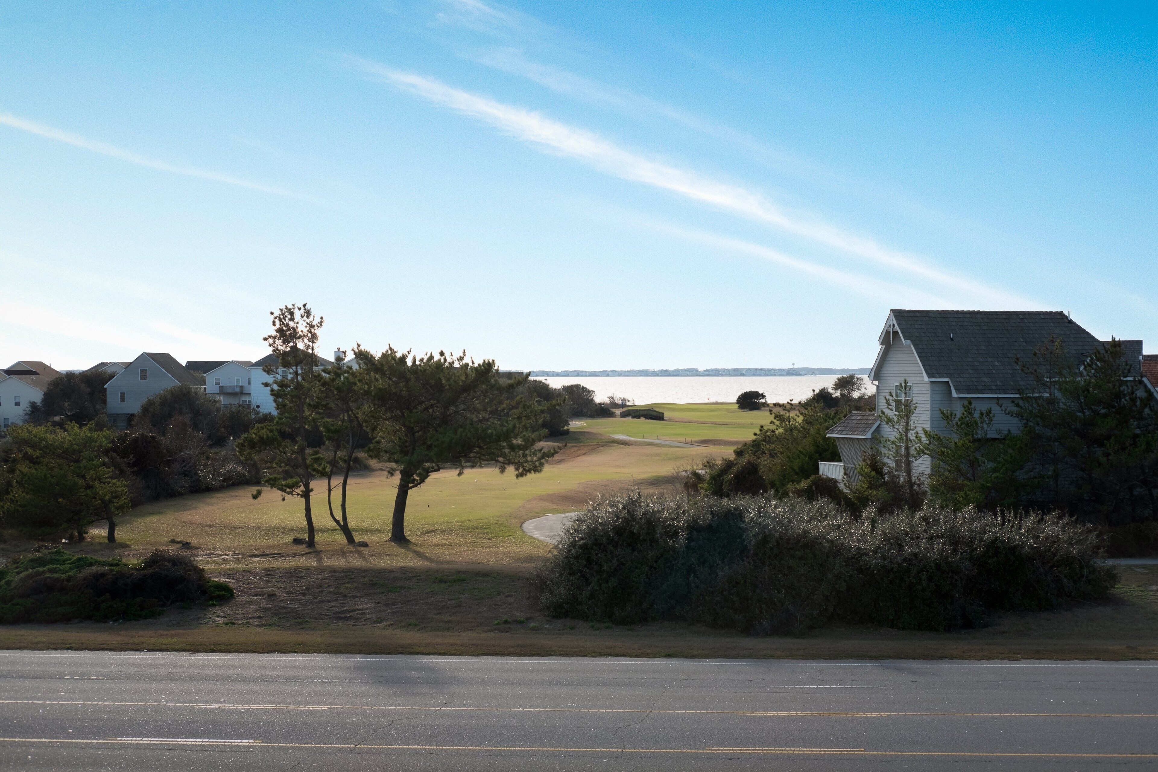 A residential area with houses, a golf course, and a road.