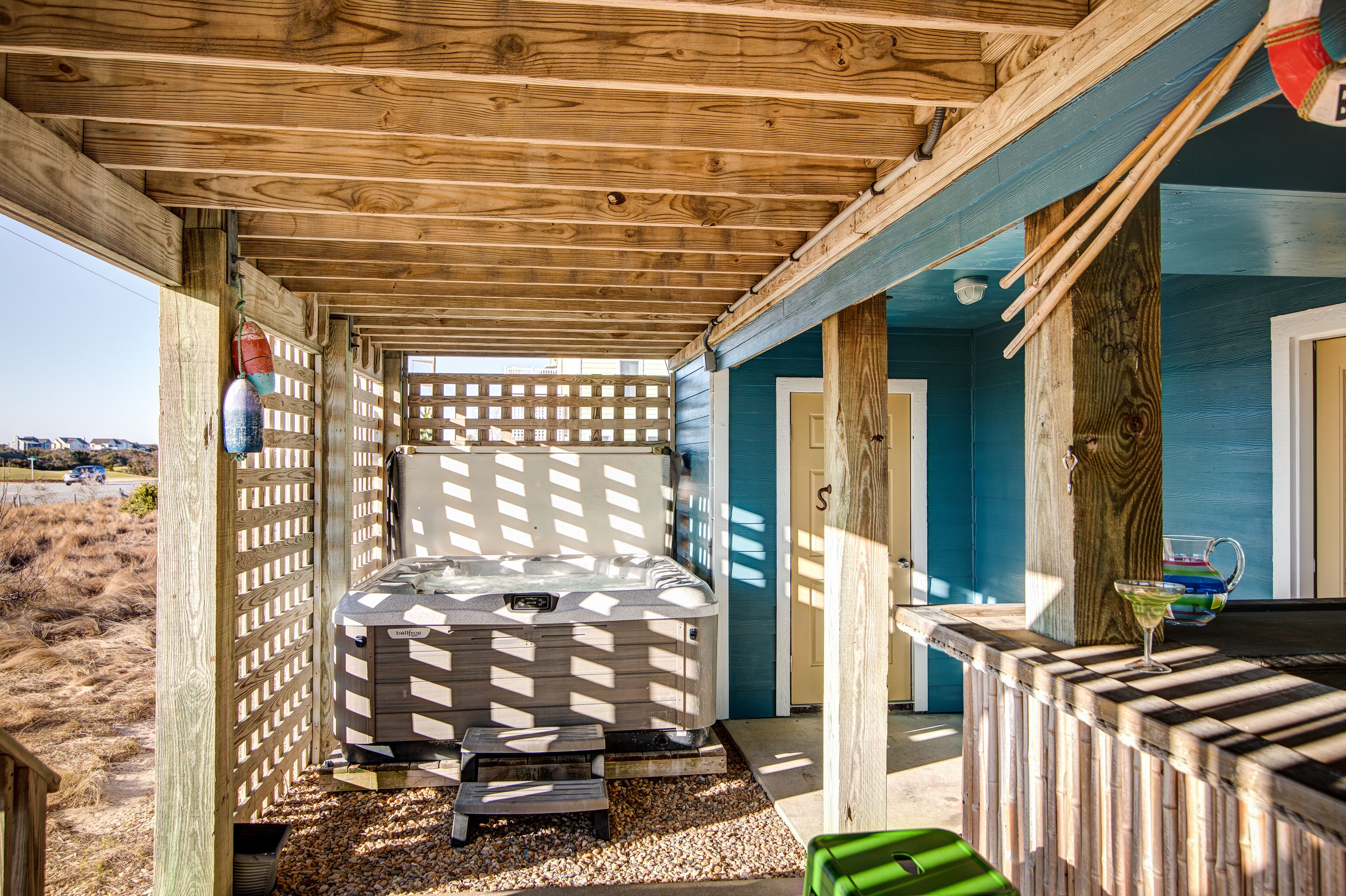 A wooden cabin with a hot tub, a small deck, and a door leading to a blue room.