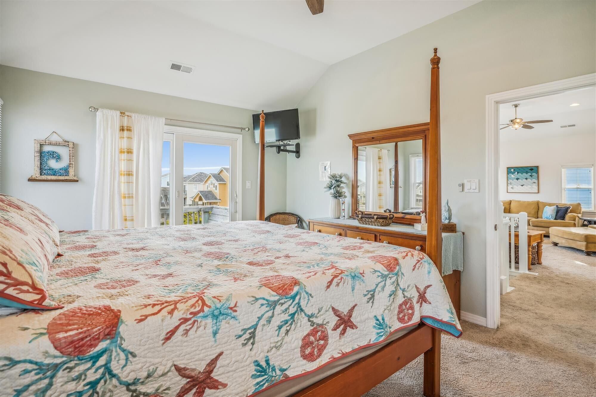 A bedroom with a four-poster bed, a dresser, a mirror, and a view of the outside.