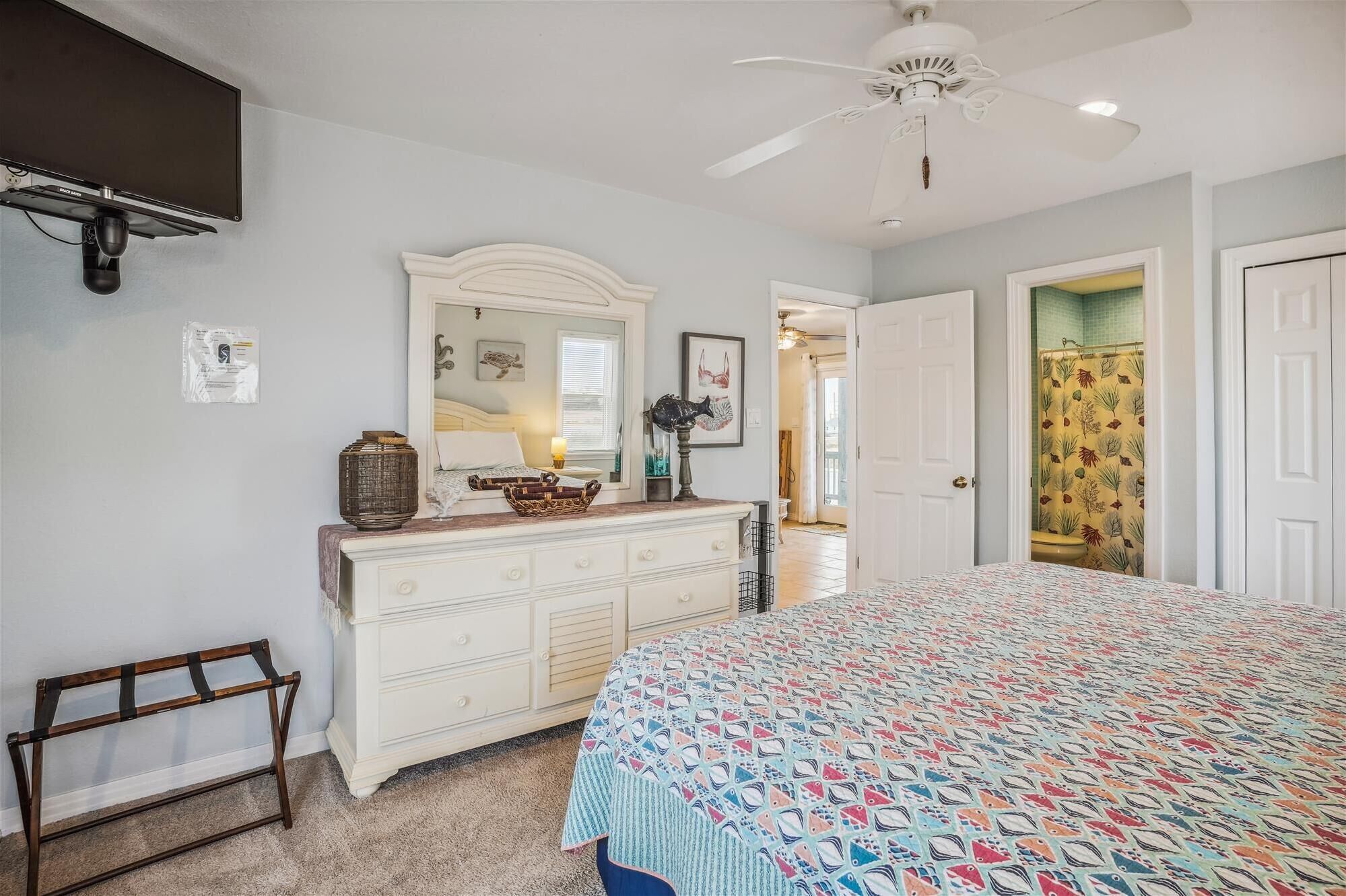 A bedroom with a bed, dresser, and a ceiling fan.
