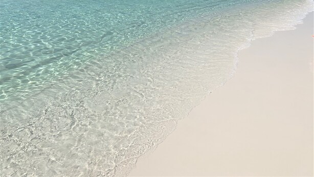 Une plage à l’eau turquoise et au sable blanc.