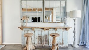 Un bar en bois rustique, avec deux tabourets, un miroir et une lampe.