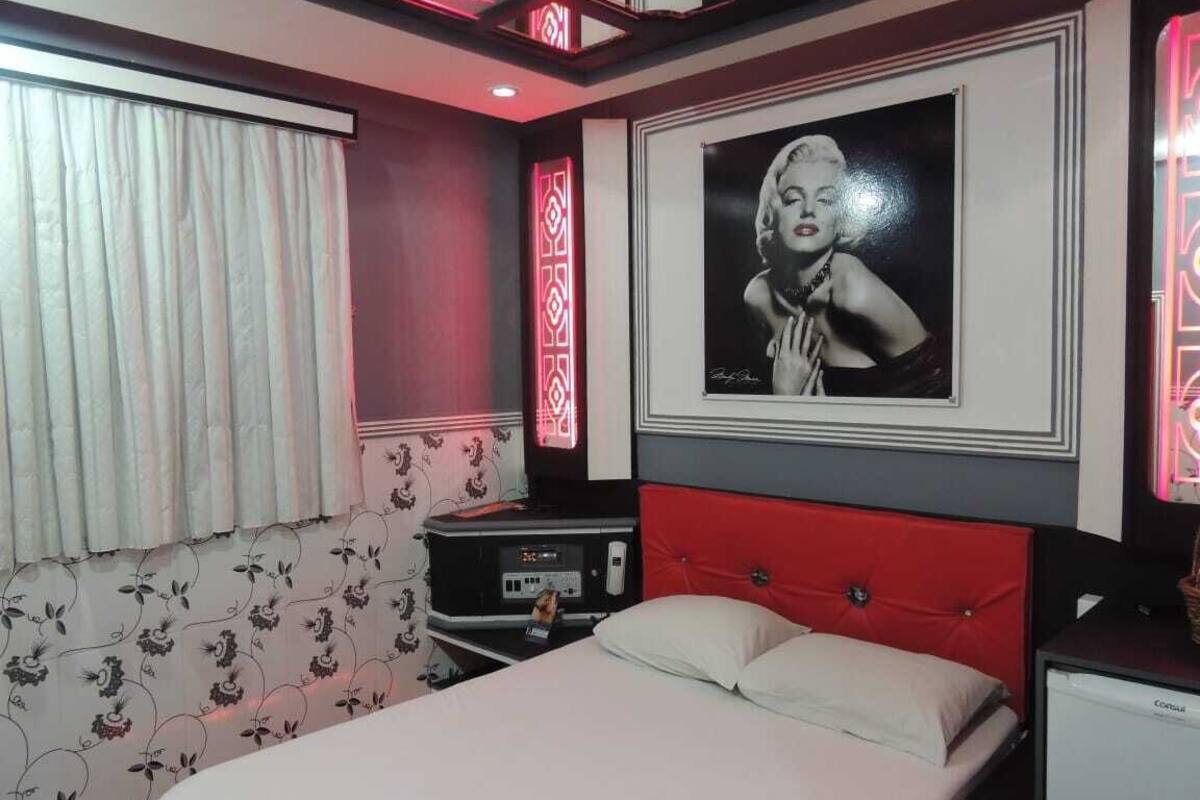 A hotel room with a bed, a bedside table, a TV, and a wall-mounted picture.