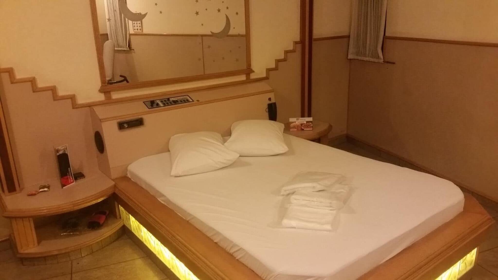 A hotel room with a bed, nightstands, a mirror, and a small table.
