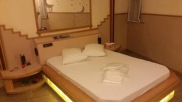 Een hotelkamer met een bed, nachtkastjes, een spiegel en een klein tafeltje.