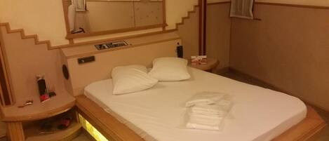 A hotel room with a bed, nightstands, a mirror, and a small table.