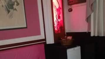 Un dormitorio con cama, mesita de noche, lámpara de pared y un cuadro enmarcado.