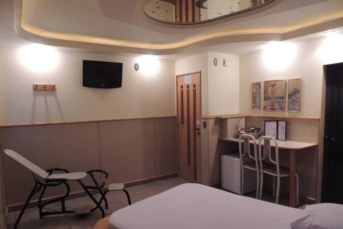 A hotel room with a bed, a desk, a chair, a television, and a small refrigerator.