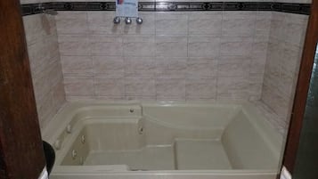 A bathroom with a bathtub, tiled walls, and a showerhead.