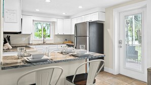 Una cocina moderna con armarios blancos, un refrigerador negro y una encimera de mármol.