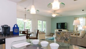 A modern kitchen with a glass dining table, white bowls, and a coffee maker.