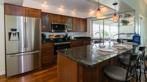 A modern kitchen with stainless steel appliances, wooden cabinets, and a granite countertop.