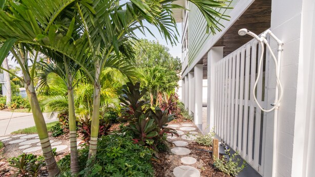 A garden pathway leading to a white fence with a water feature.