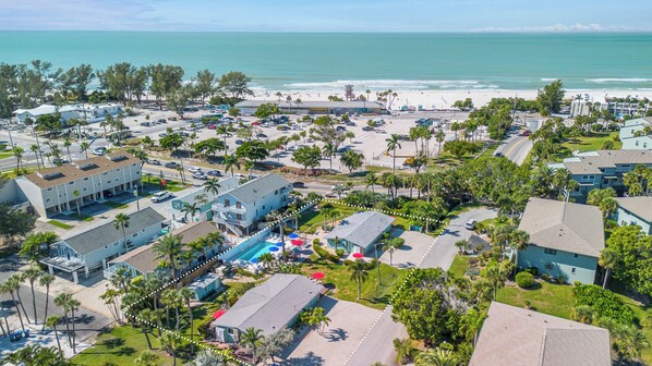 A coastal hotel with multiple buildings, a swimming pool, and a beach view.