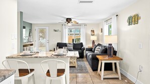 Un salon moderne avec un coin repas, un ventilateur de plafond et une vue sur l’extérieur.