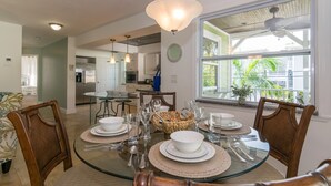 Comedor con mesa de vidrio dispuesta para cuatro personas, rodeado de sillas de mimbre.