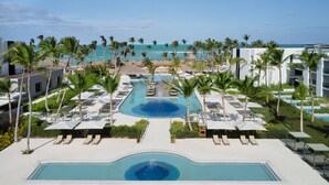 Een resort met een zwembad, ligbedden en palmbomen.