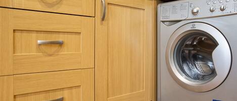 Una cocina moderna con armarios de madera y una lavadora de acero inoxidable.